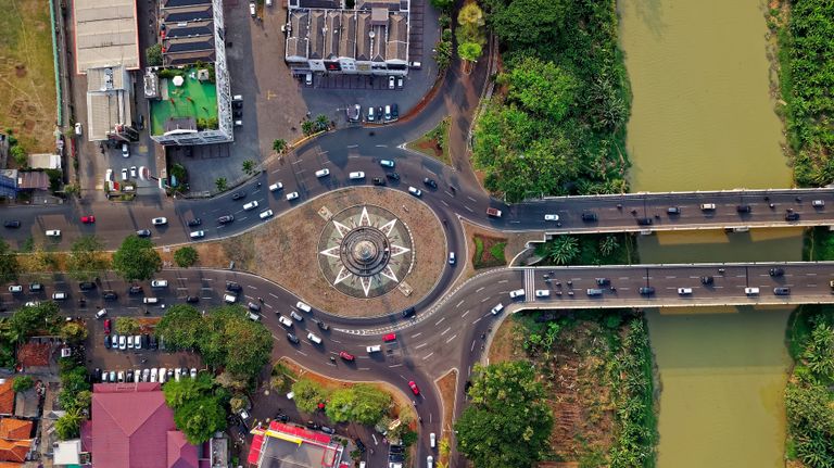 Drone view of a roundabout and bridge in Kelapa Dua, showcasing urban traffic and landscape.